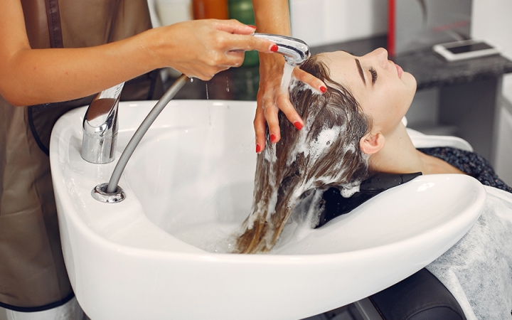 Hairdresser washing head her client. Woman in a hair salon
